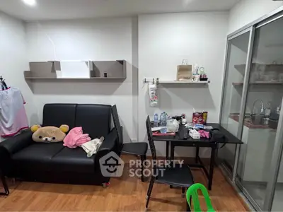 Cozy living room with black sofa, dining table, and modern shelving in a compact apartment.