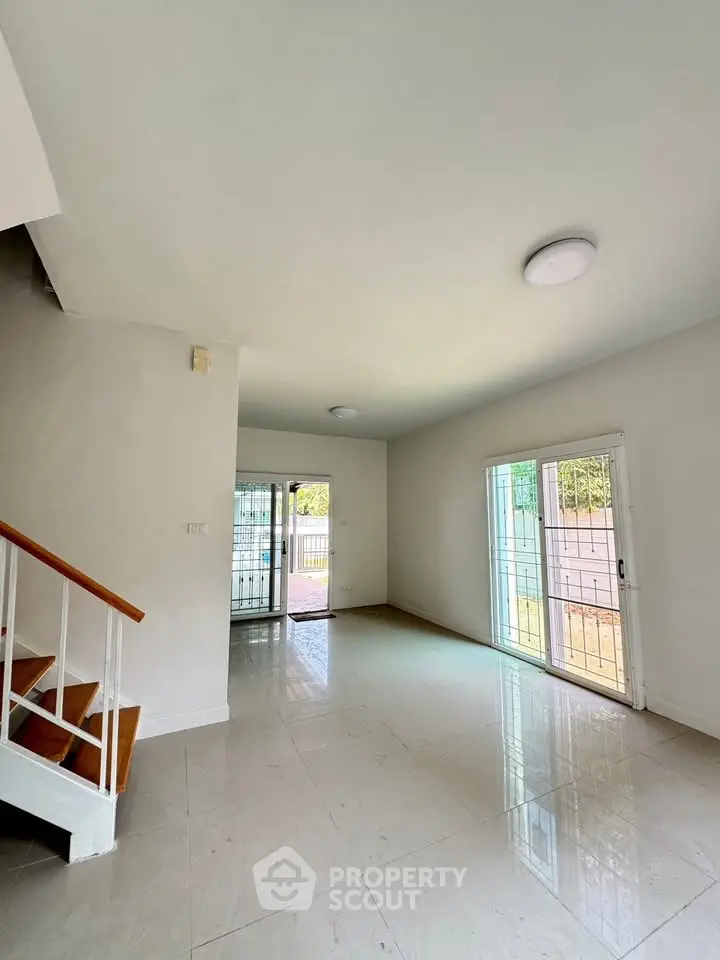 Spacious living room with natural light and modern staircase in a contemporary home.