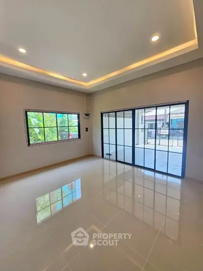 Spacious living room with large windows and glossy tiled floor, offering abundant natural light and modern design.