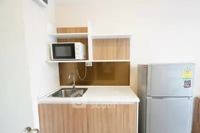 Compact kitchen with microwave and fridge in modern apartment