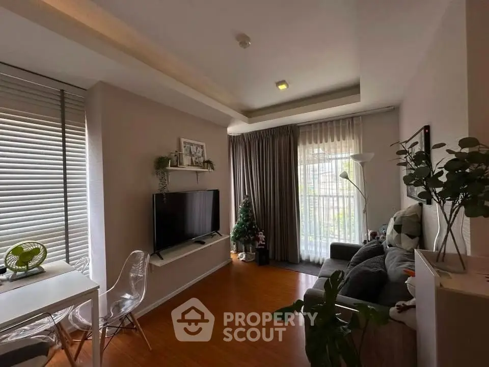 Modern living room with stylish decor and natural light, featuring a cozy seating area and a sleek TV setup.