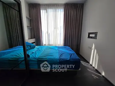 Modern bedroom with blue bedding and large window, featuring sleek design and ample natural light.