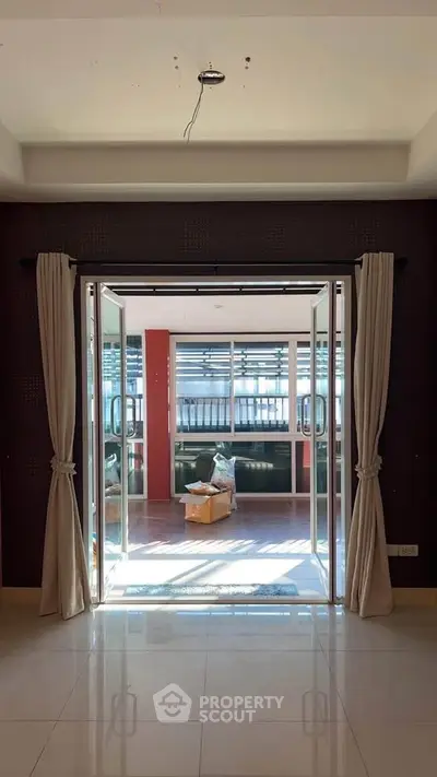 Spacious interior with open double doors leading to a sunlit room, ideal for modern living.