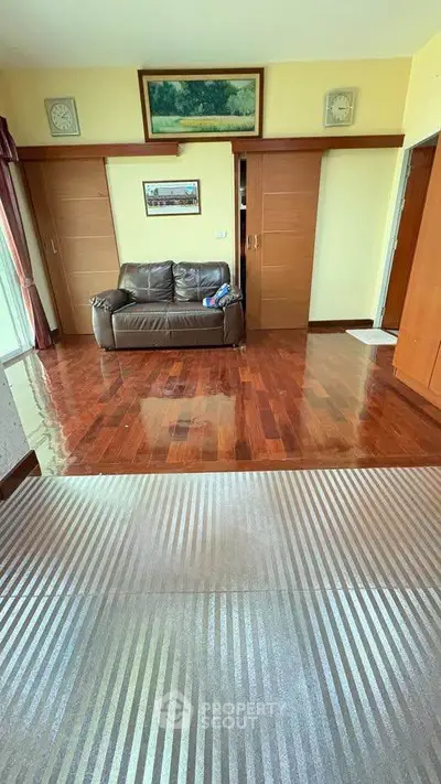 Spacious living room with wooden flooring and cozy sofa, perfect for relaxation.