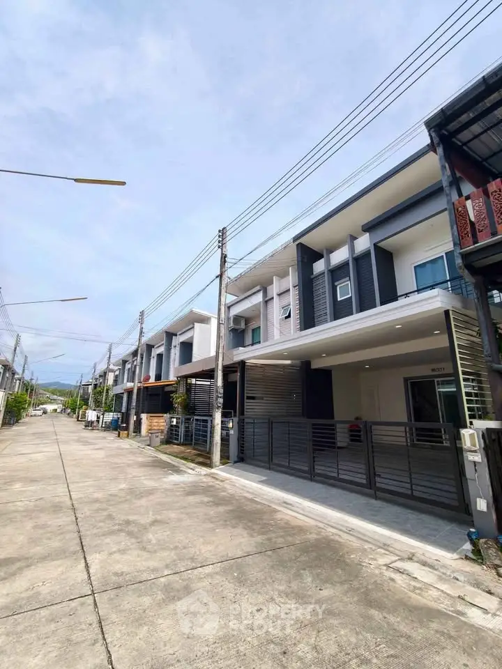 Modern townhouse exterior with sleek design and spacious driveway in a suburban neighborhood.
