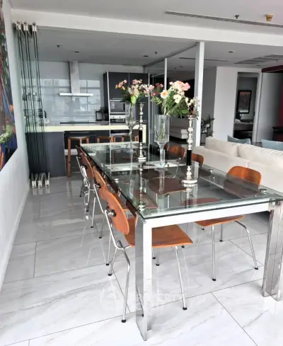 Modern dining area with glass table and elegant kitchen in open layout apartment.