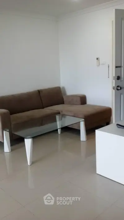 Modern living room with sleek glass coffee table and cozy brown sofa