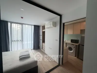 Modern apartment interior with bedroom and kitchen featuring large windows and sleek design.