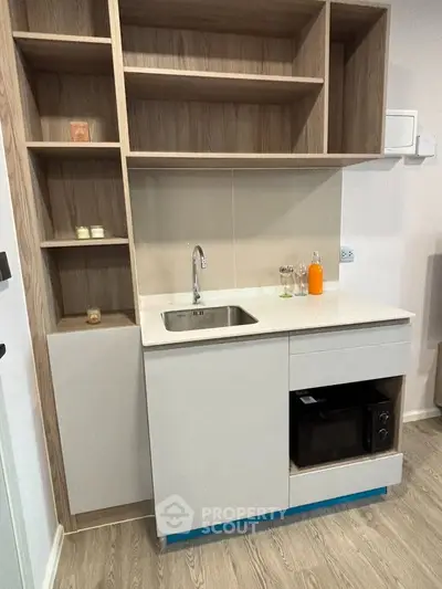 Modern compact kitchen with sleek cabinetry and built-in microwave, ideal for urban living.