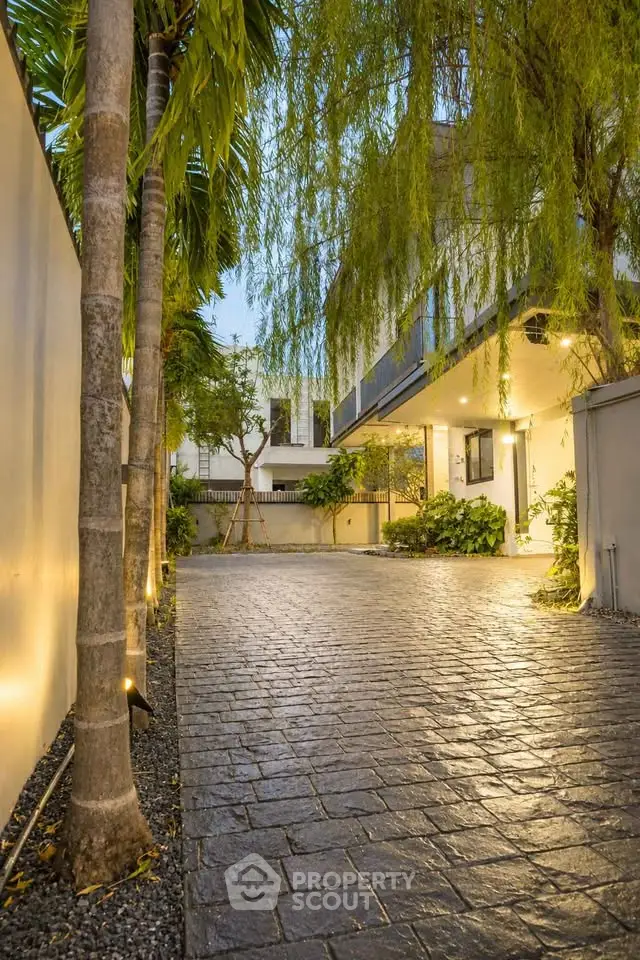 Charming driveway entrance with lush greenery and modern lighting, perfect for a welcoming home ambiance.