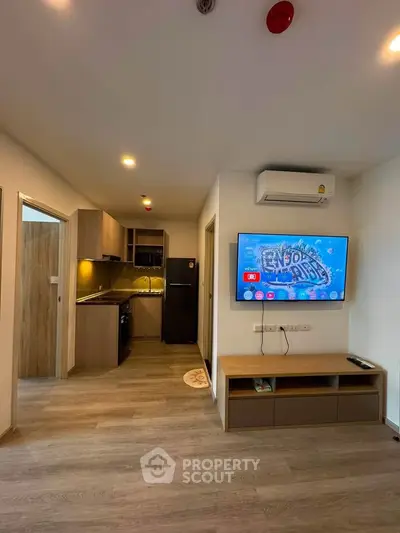 Modern living room with open kitchen, featuring sleek wooden flooring and contemporary furnishings.