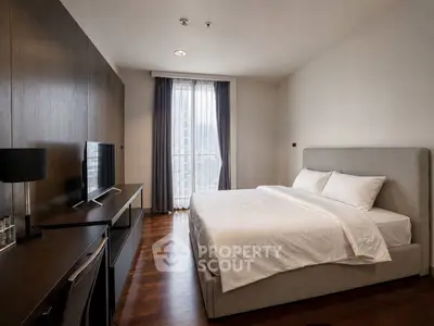 Luxurious bedroom with modern furnishings and large window offering city views.