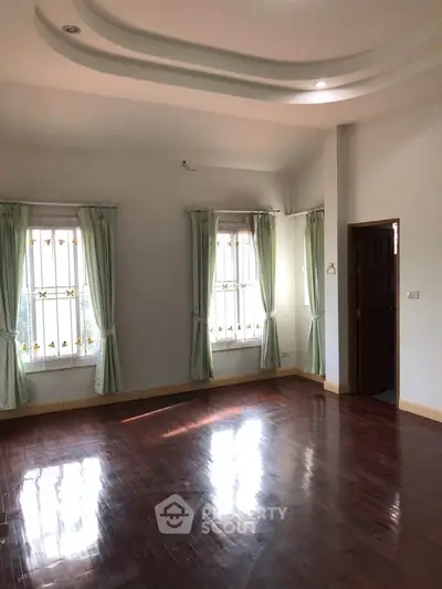 Spacious living room with elegant hardwood floors and natural light through large windows.