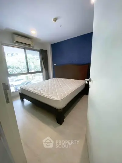 Spacious bedroom with large window and modern furnishings in a stylish apartment.