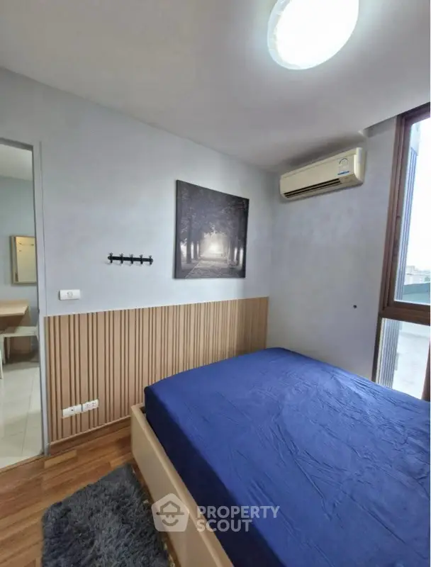 Cozy bedroom with blue bedding and modern decor in a bright apartment.