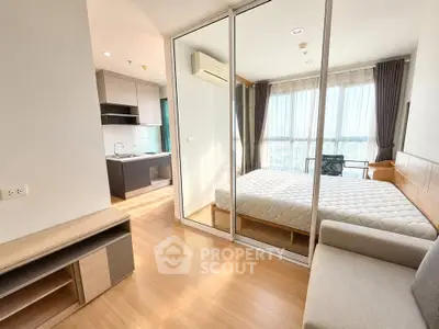 Modern apartment with open kitchen and cozy bedroom featuring large windows and natural light.