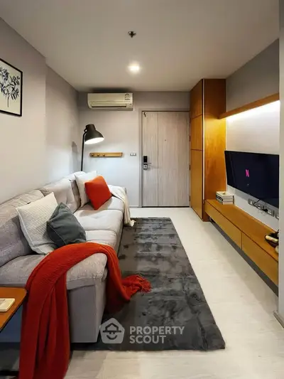 Modern living room with cozy sofa, stylish decor, and wall-mounted TV in a chic apartment.