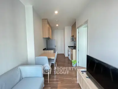 Modern apartment interior with open layout, featuring a cozy living area, dining space, and a compact kitchen.