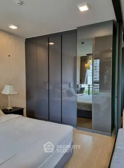 Modern bedroom with sleek wardrobe and city view from window.