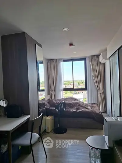 Cozy bedroom with large window offering scenic view, modern furnishings, and ample natural light.