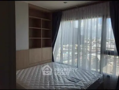 Spacious bedroom with large windows offering a stunning city view, perfect for urban living.