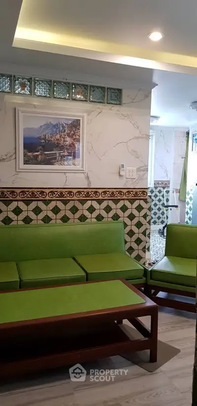 Charming living room with vibrant green seating and decorative wall tiles, perfect for cozy gatherings.