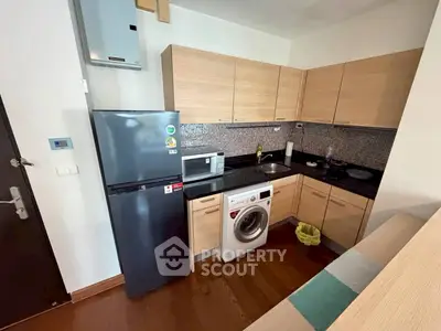 Modern kitchen with sleek appliances and wooden cabinetry in a compact layout.