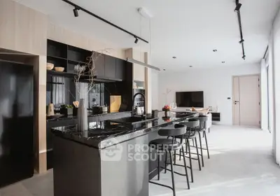 Modern open-layout kitchen with sleek black countertops and stylish bar seating in a contemporary home.