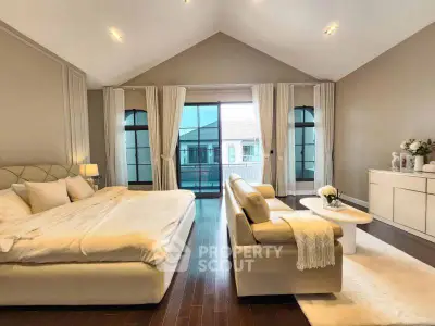 Luxurious bedroom with elegant decor and spacious layout, featuring a cozy seating area and large windows.