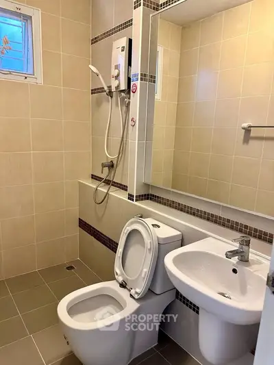Modern bathroom with sleek fixtures and neutral tiles, featuring a shower and toilet for a clean, contemporary look.