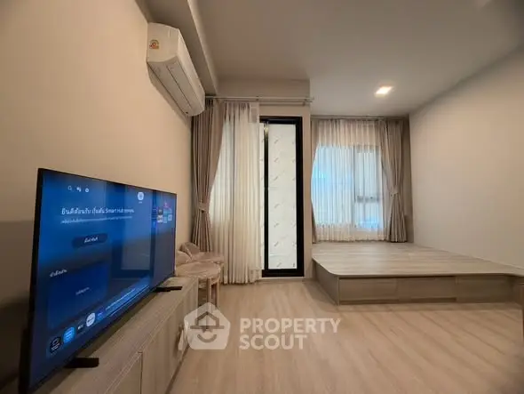 Modern living room with TV, air conditioning, and stylish curtains in a cozy apartment.