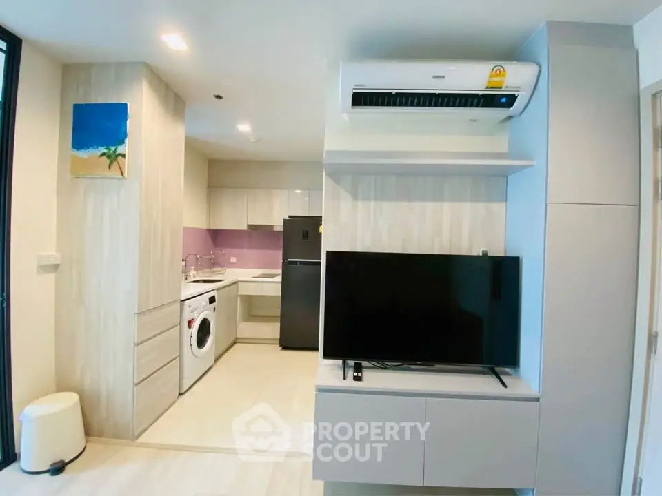 Modern open-plan living room with kitchen, featuring sleek appliances and stylish decor.