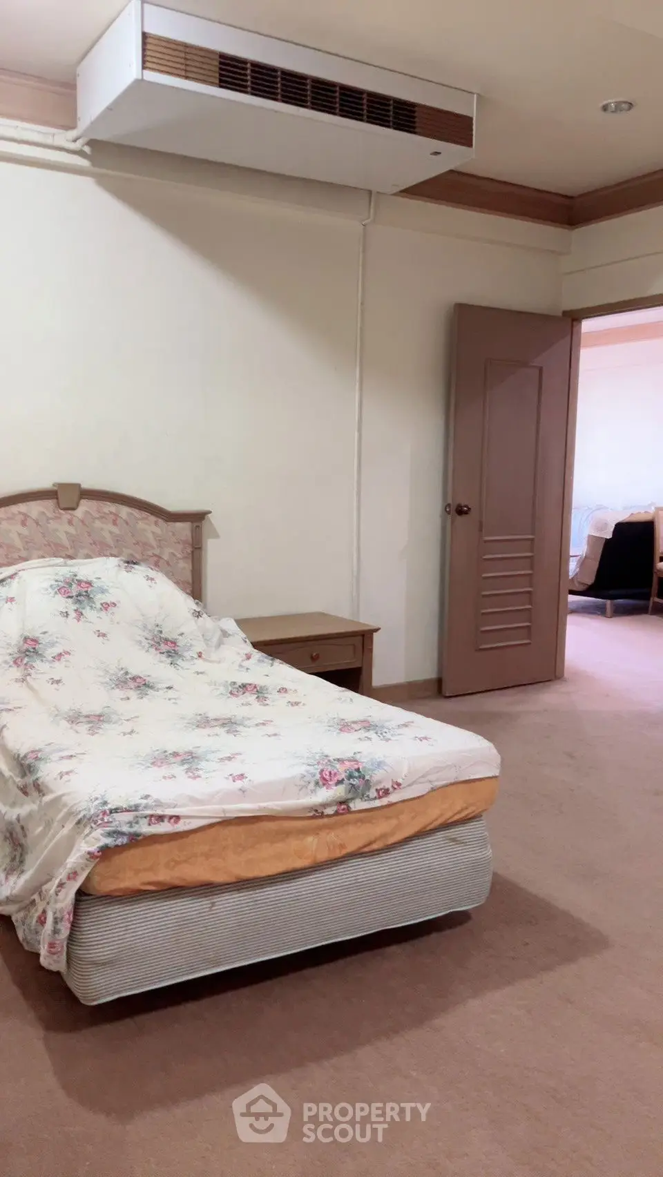 Cozy bedroom with floral bedding and open door to living area