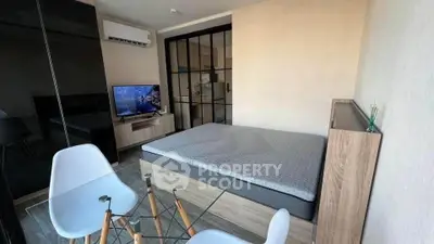 Modern studio apartment with glass table and wall-mounted TV