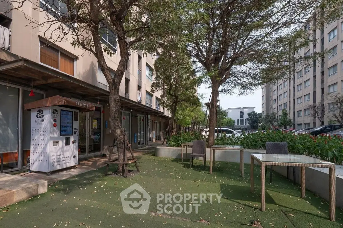 Charming outdoor seating area in modern residential complex with lush greenery and convenient amenities.