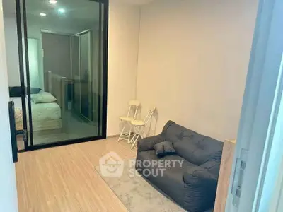 Cozy living room with modern decor and glass partition leading to bedroom.