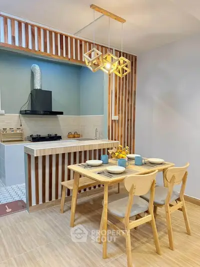 Modern kitchen with open layout and stylish dining area featuring wooden accents and contemporary lighting.