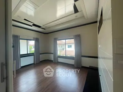 Spacious empty room with large windows and wooden flooring, ideal for customization.