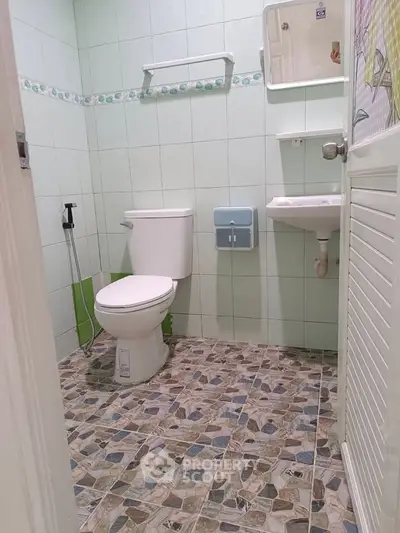 Compact bathroom with tiled floor and essential fixtures in a cozy home setting.