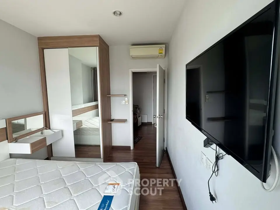 Modern bedroom with wall-mounted TV and stylish wardrobe in a cozy apartment.