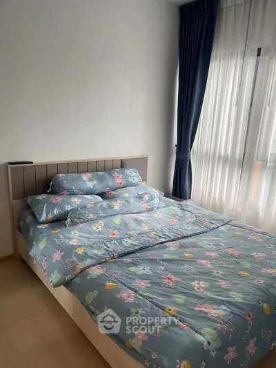Cozy bedroom with floral bedding and large window with curtains