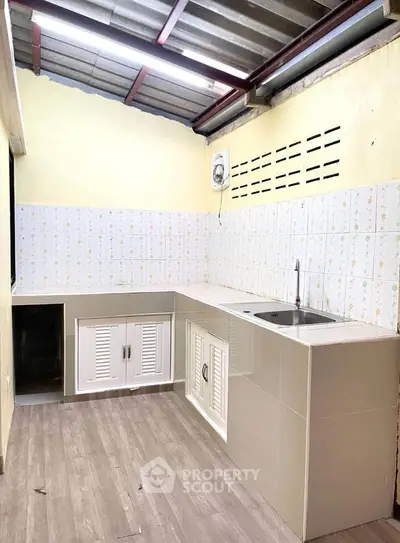 Spacious kitchen with modern cabinetry and tiled backsplash, featuring a sleek countertop and stainless steel sink.