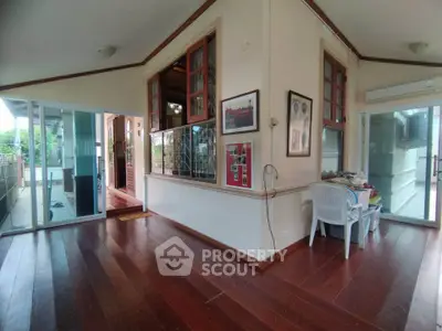 Spacious living area with wooden flooring and large windows in a modern home.