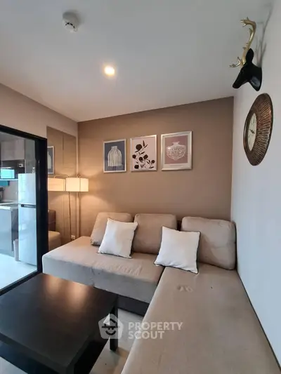 Modern living room with cozy beige sofa, stylish decor, and warm lighting in a contemporary apartment.