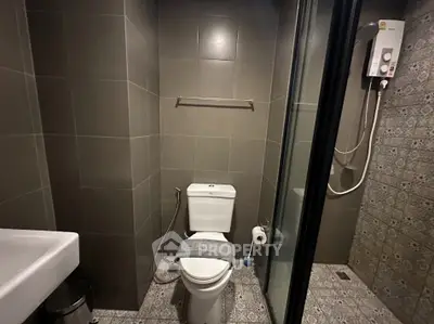 Modern bathroom with shower and sleek tile design, featuring a compact layout and contemporary fixtures.