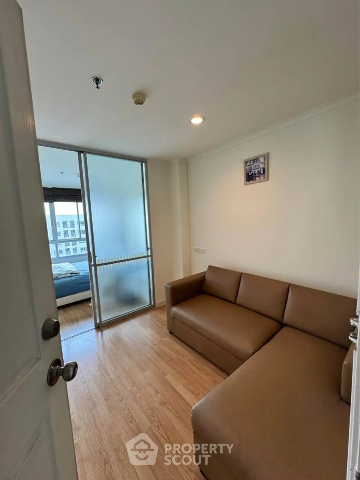 Cozy apartment with wooden flooring and modern furnishings, featuring a comfortable living area and a glimpse of the bedroom.