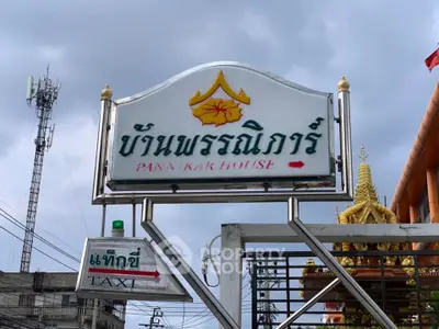 Signage for Pannakak House with nearby taxi stand in urban setting.