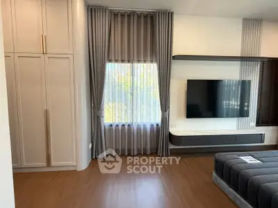 Modern living room with sleek TV setup and elegant curtains, featuring stylish wooden flooring.