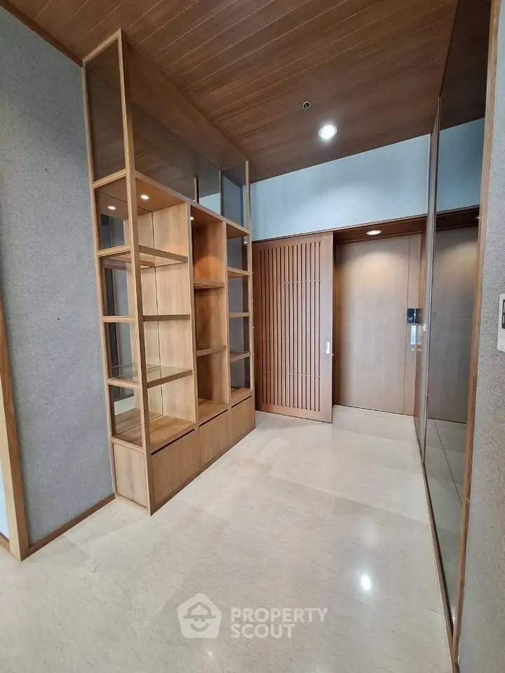 Modern apartment entrance with sleek wooden shelving and elegant marble flooring.
