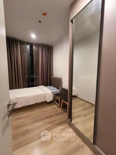 Modern bedroom with wooden flooring and large window with curtains